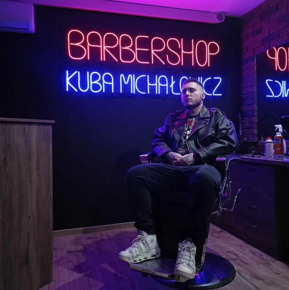 Barbershop Kuba Michałowicz interior with barber seated under neon sign